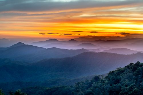 Free Breathtaking view of a mountain range at sunset with dramatic skies and mist. Stock Photo
