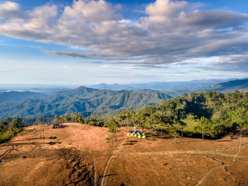 Free Aerial view of colorful tents on a mountain peak under a vibrant sky. Stock Photo