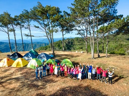 Free A lively group enjoying a vibrant camping trip in a lush forest background with colorful tents and clear skies. Stock Photo