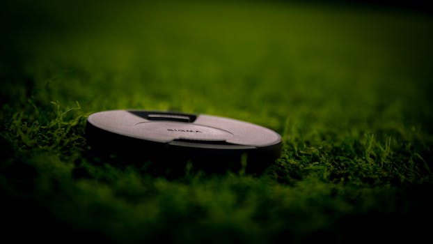 A detailed close-up of a Sigma lens cap resting on lush green grass, emphasizing nature and photography.