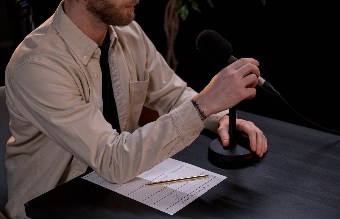 A man prepares for a podcast in a studio with a microphone and notes.