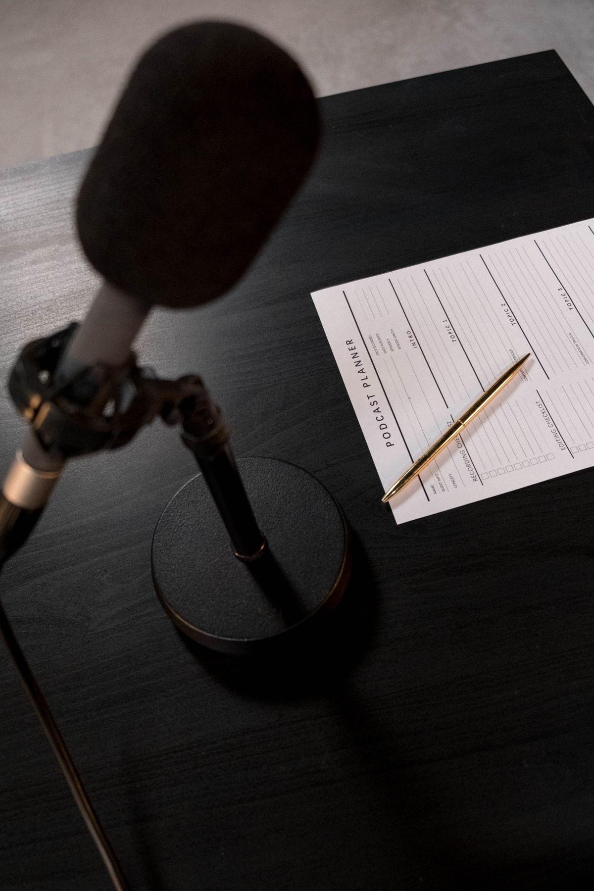 Podcast planner beside microphone on a dark desk