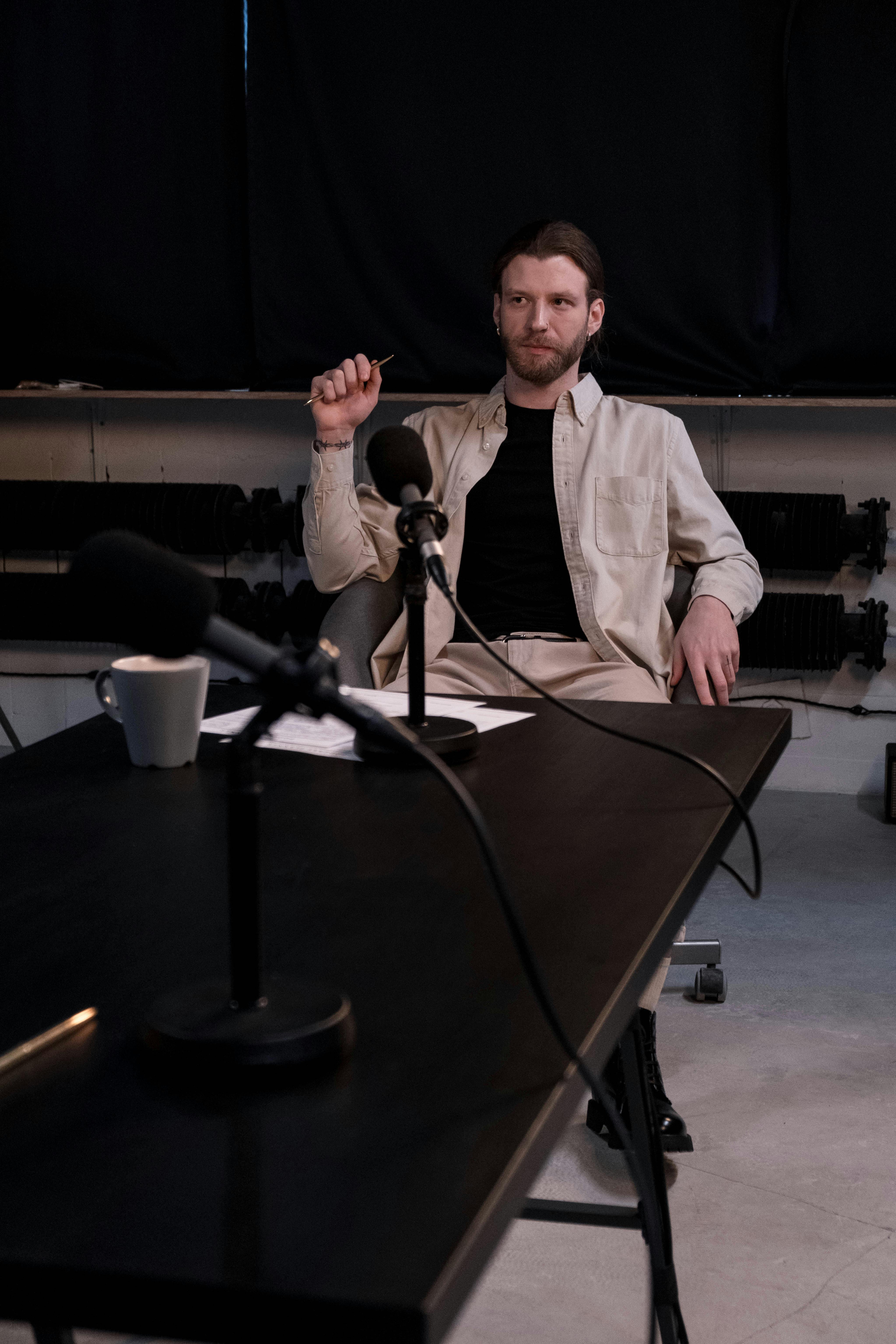 A man sitting across a table during an interview, gesturing with his hands while speaking.