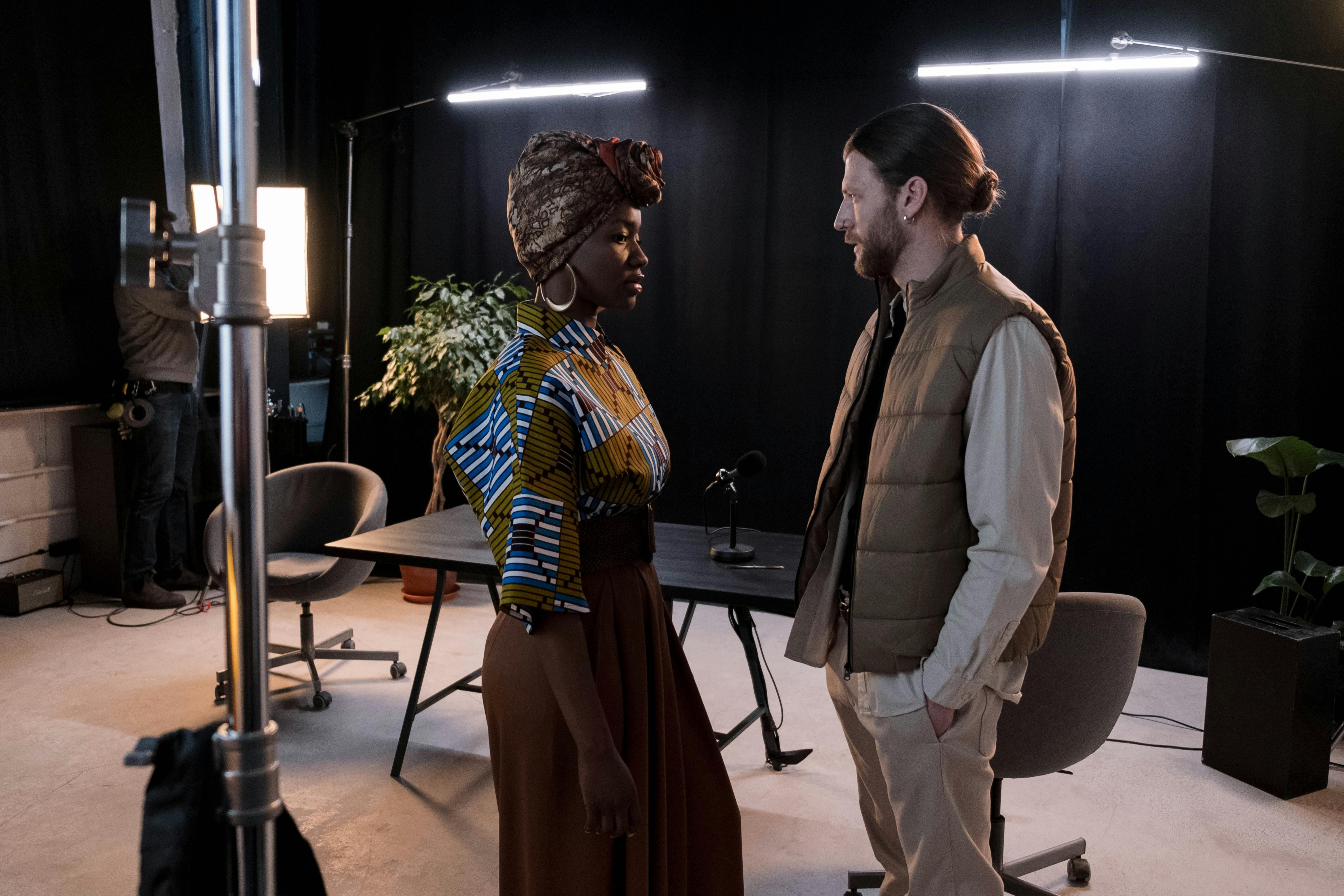 Diverse models in a fashionable studio setup with lighting equipment and a table.