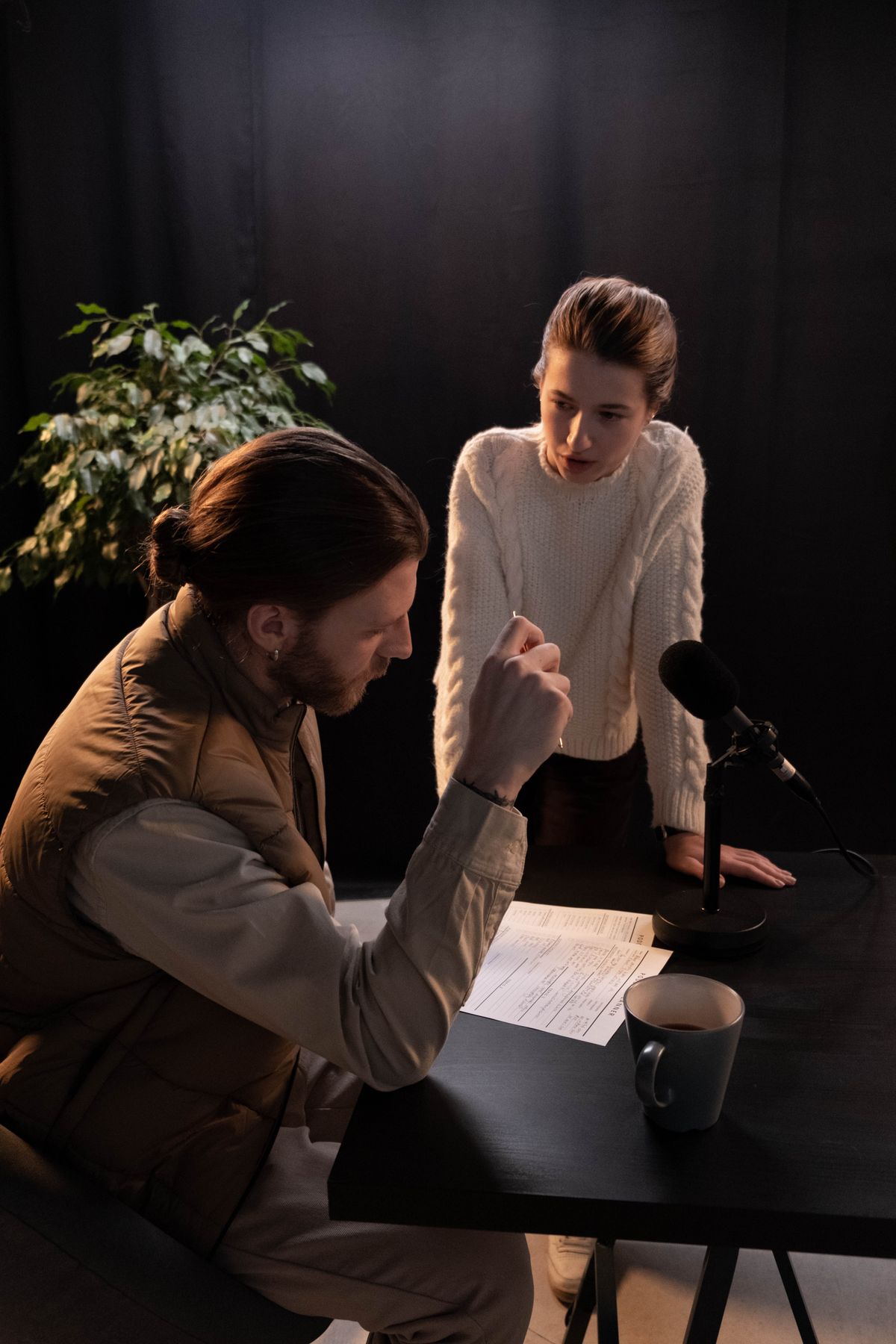 Two people talking across a table in a darkened radio studio — photo by cottonbro studio on Pexels