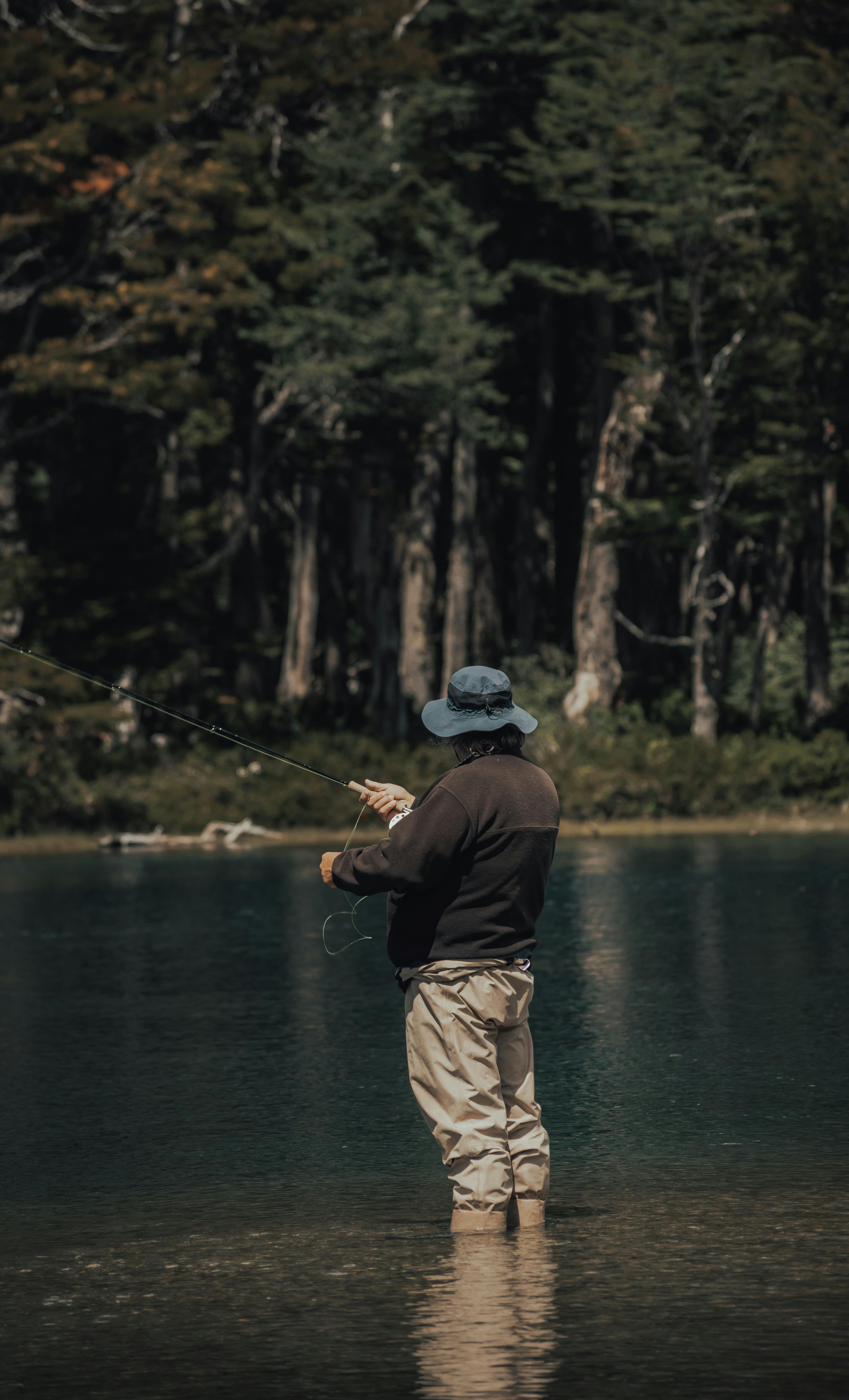 A man enjoys fishing in a tranquil forest lake, reflecting the beauty of nature.