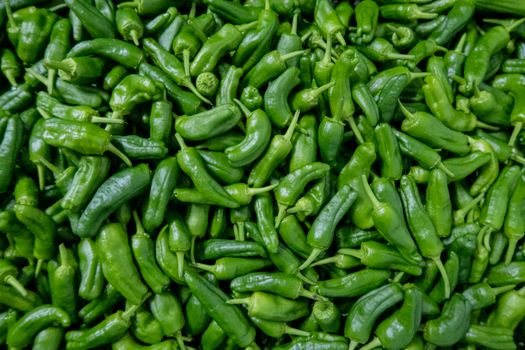 A large pile of fresh green chili peppers perfect for food photography and culinary uses.