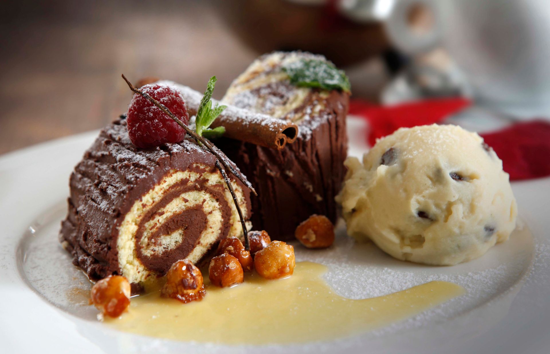 Delicious chocolate Swiss roll served with vanilla ice cream and candied nuts on a ceramic plate.