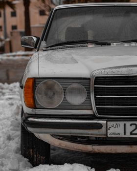 Close-up of a classic vintage car with snow cover in Amman, showcasing winter's chill.