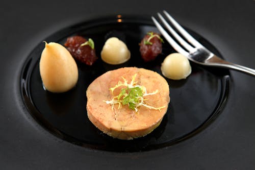Foto de stock gratuita de un foie gras con tenedor de acero en un plato de cerámica
