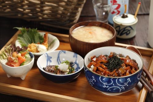 Free A beautifully arranged Japanese meal featuring rice bowl, miso soup, and side dishes on a wooden tray. Stock Photo