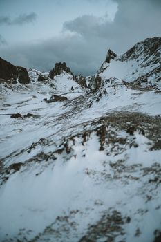 A breathtaking view of a snowy mountain range under a moody cloudy sky, capturing the essence of winter's beauty.