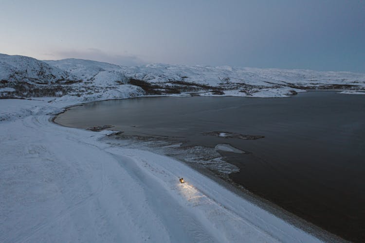 A Snow Covered Landscape Near The Lake