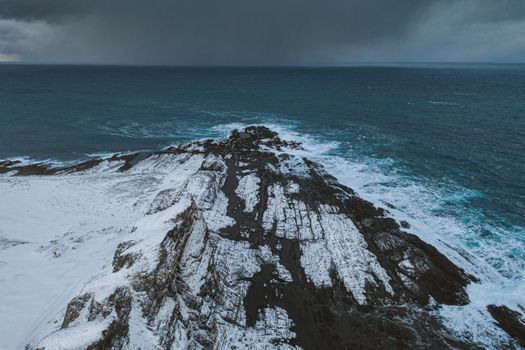 Aerial view of snow-covered rock formations meeting the ocean in Vayda-Guba, Russia.