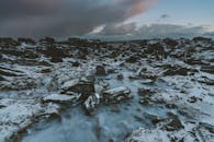 在黄昏时分拍摄的迷人的冰冻沿海景观，在戏剧性的冬季天空下，有冰冷的岩石