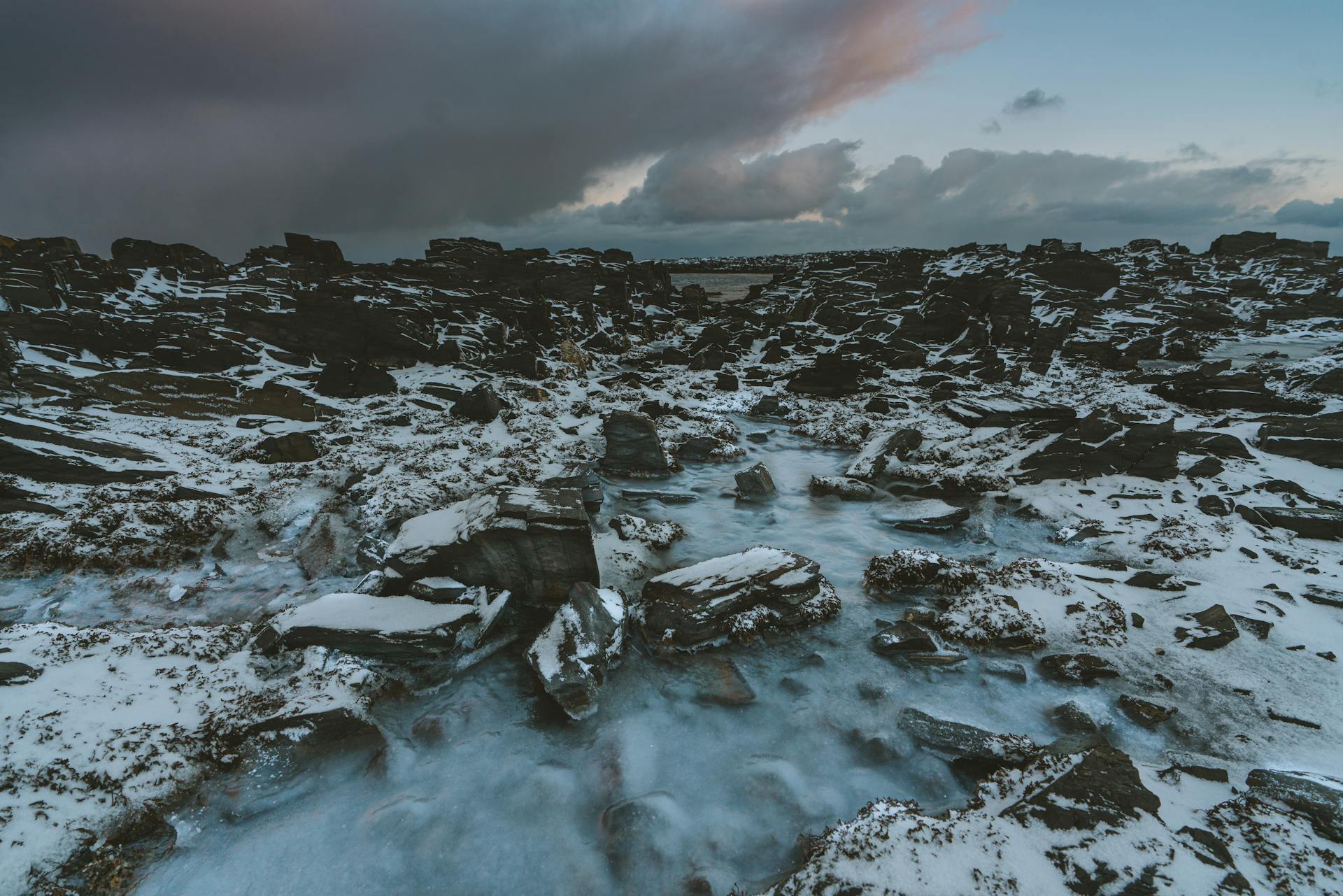 Frozen and Snow Covered Rocks on Body of Water