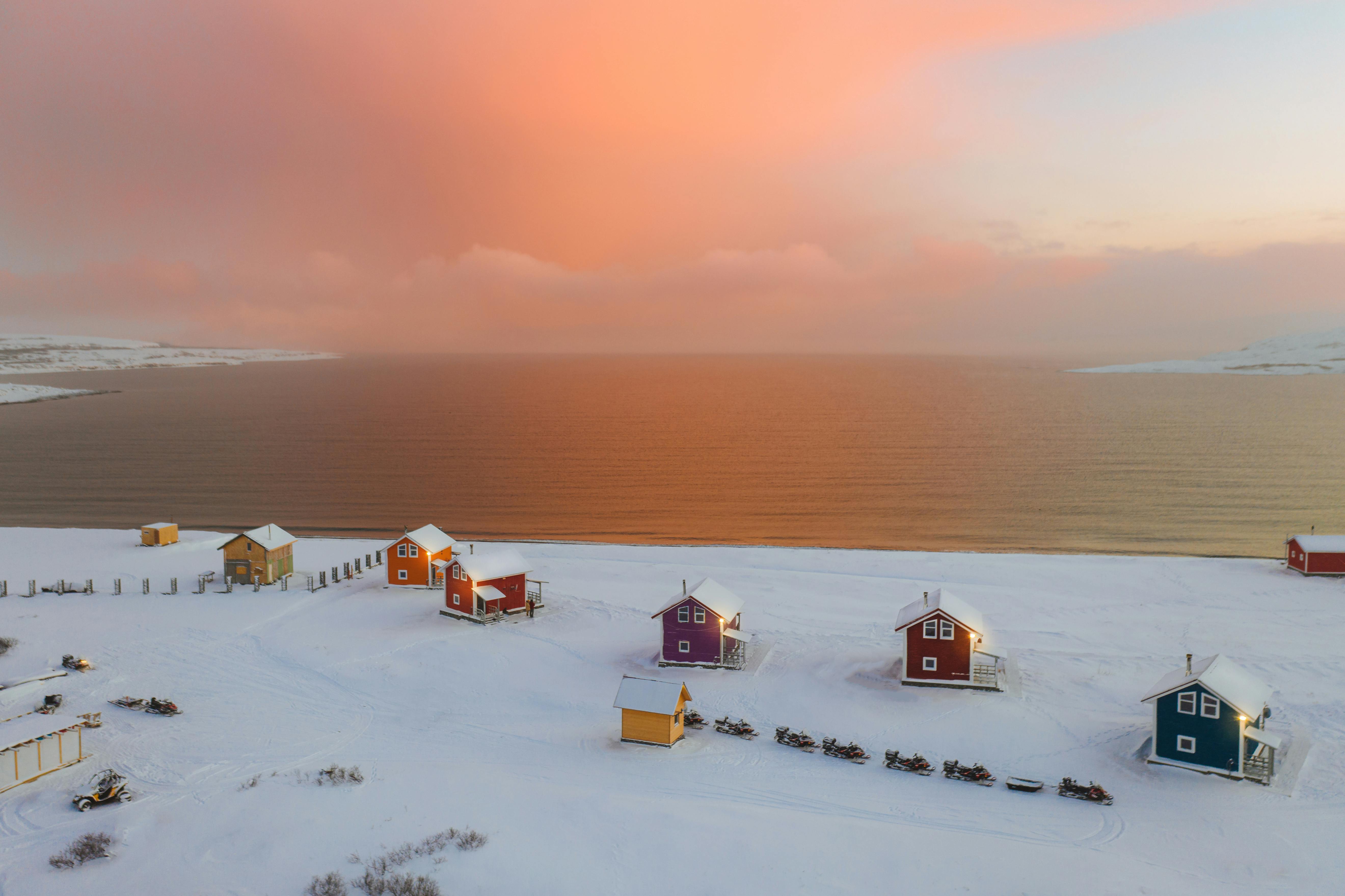 white and brown house on snow covered ground during sunset