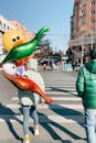 A Person Holding Balloons Walking on a Pedestrian Crossing