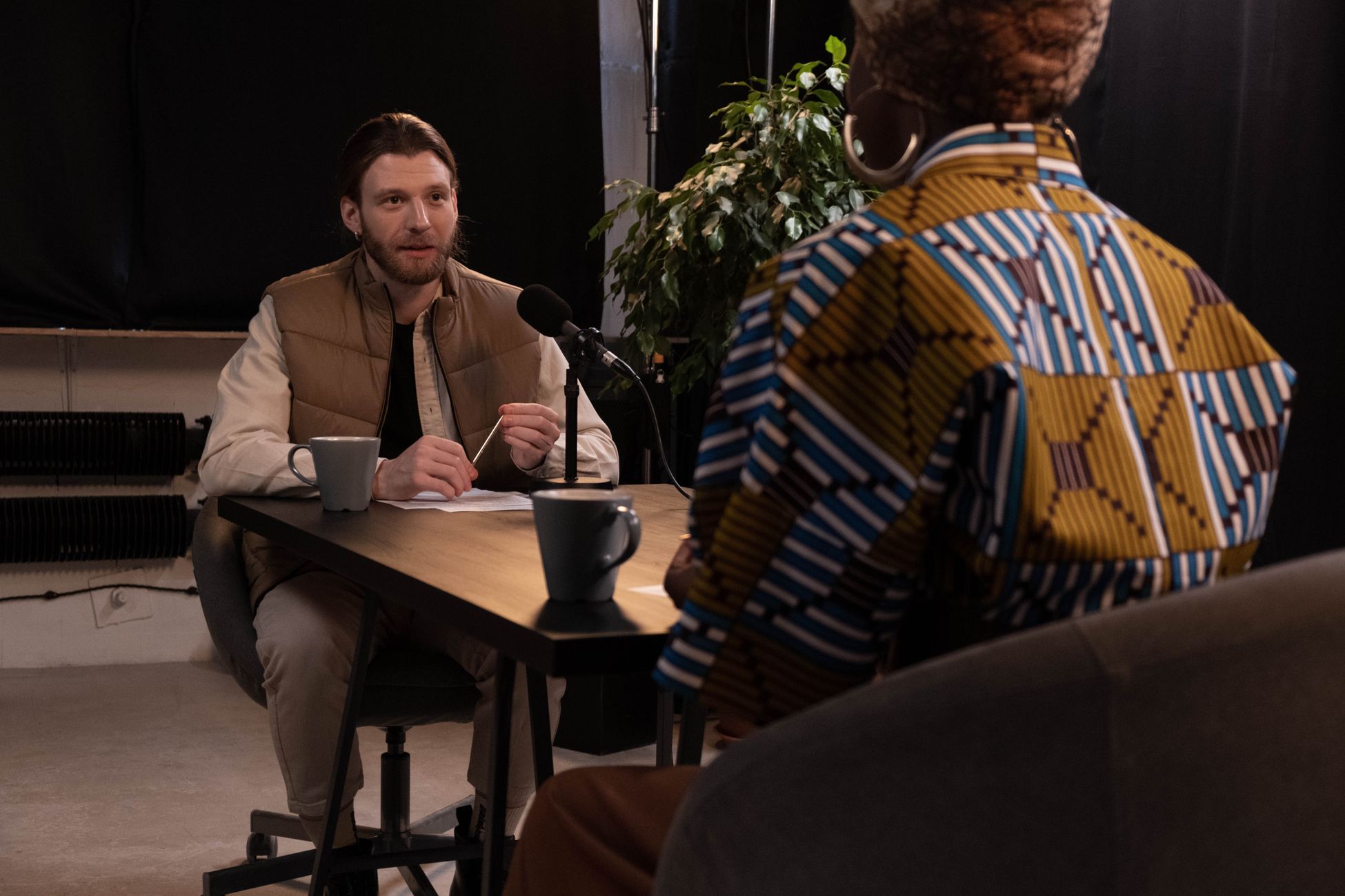 A podcast interview featuring diverse hosts in a professional studio setting with microphones and coffee mugs.