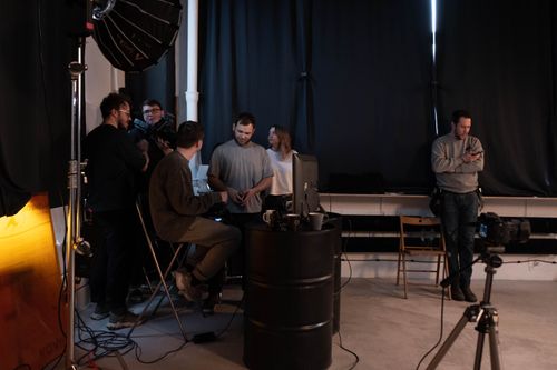 Free A group of people collaborating in a dimly lit photo studio, setting up for a creative project. Stock Photo