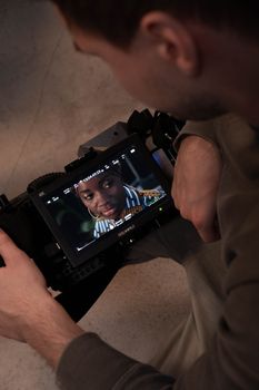Man holding camera with screen showing a woman actress in close-up.