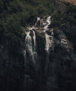 A majestic waterfall cascading over rugged cliffs surrounded by thick greenery. Captured in natural daylight.