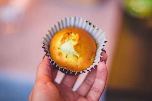 Delicious homemade muffin held in hand, perfect for a sweet snack. Showcases food's irresistible taste and texture.