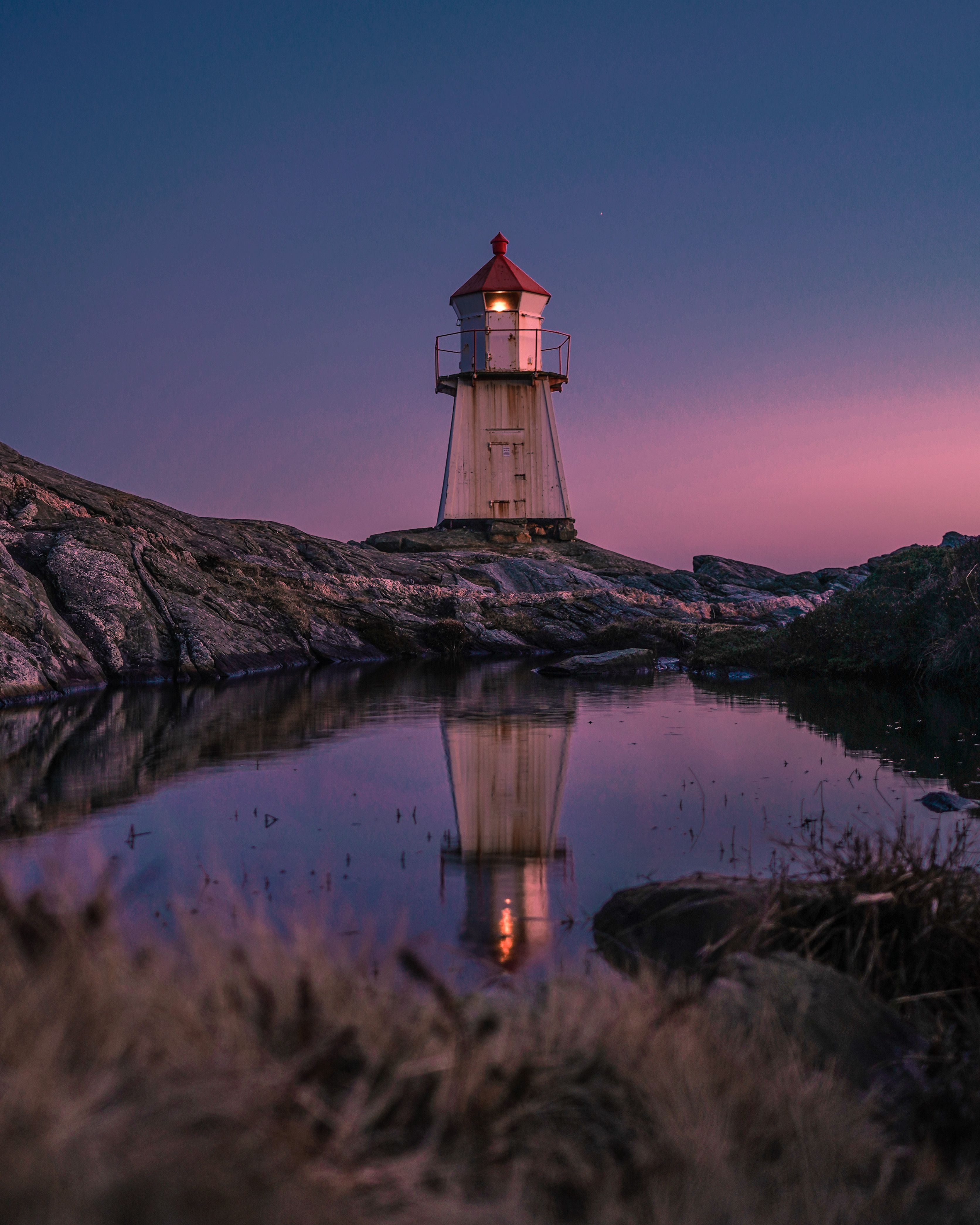 White and Red Lighthouse on Brown Rock Formation Near Body of Water ...