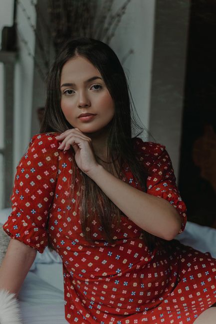 Delicate female with rouge on face and long hair looking at camera at home