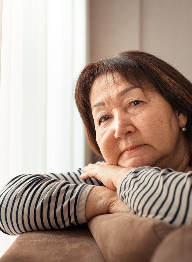 Mature Asian Woman With Wrinkles Leaning On Sofa