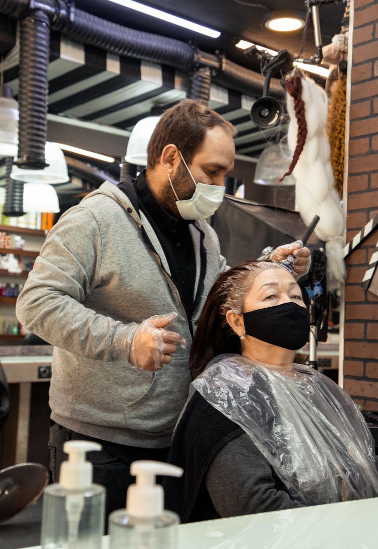 Experienced Bearded Hairdresser Dying Hair Of Senior Woman