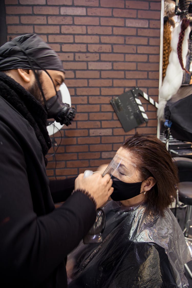 Hairstylist In Respirator Dying Hair Of Aged Woman In Mask