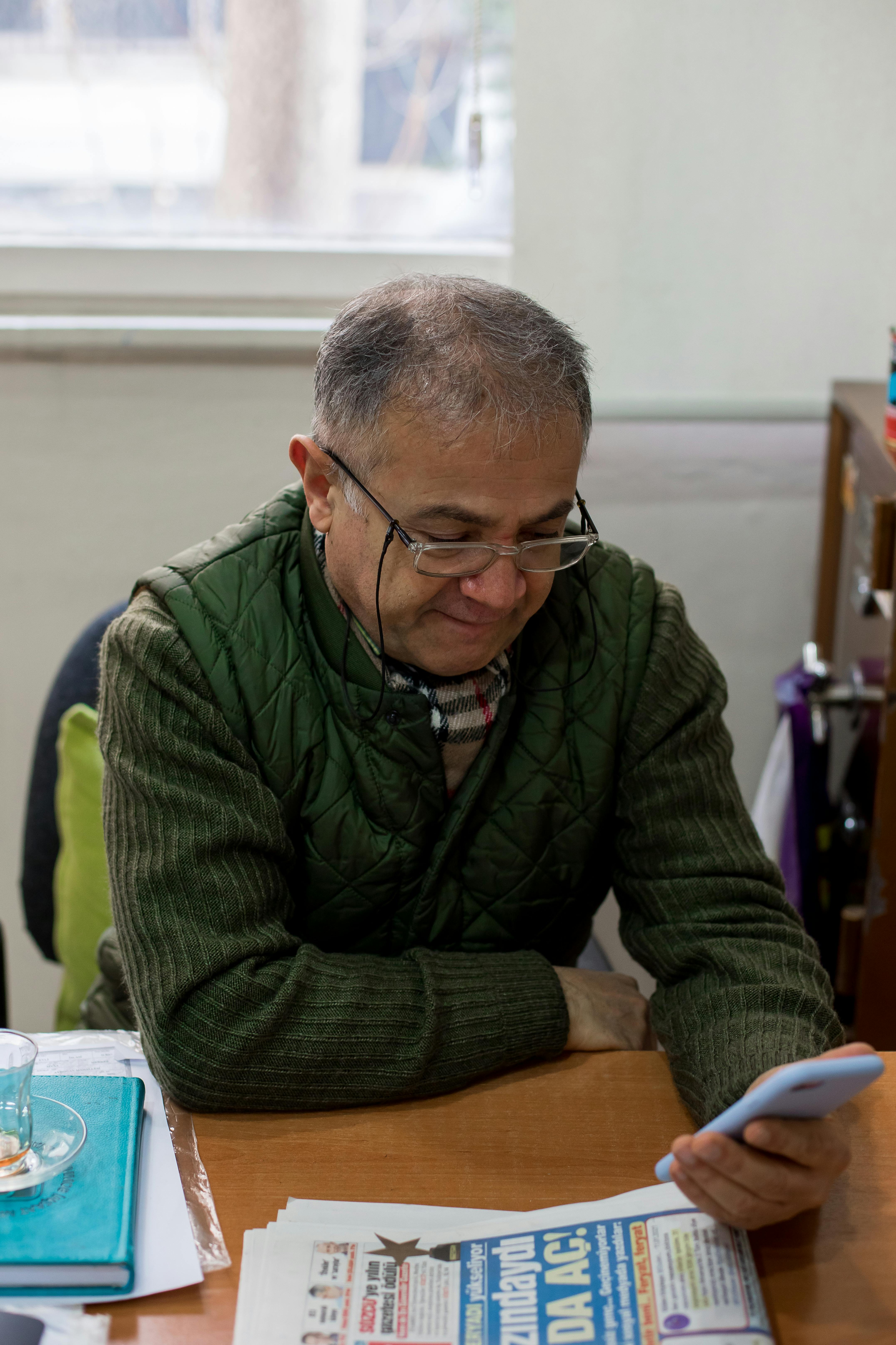 man at table using smartphone near newspaper in room