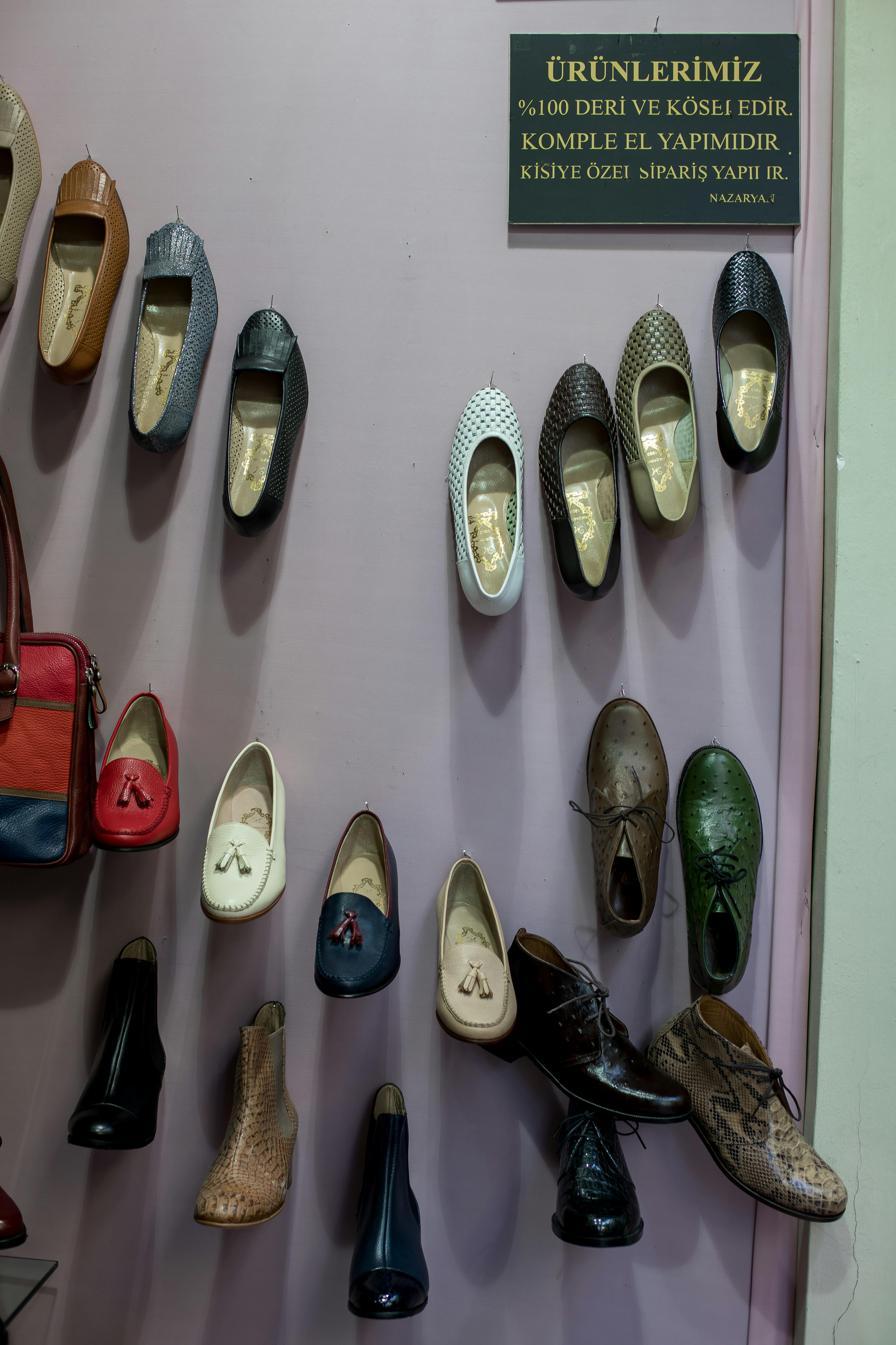 collection of handmade leather shoes hanging on wall in manufacture