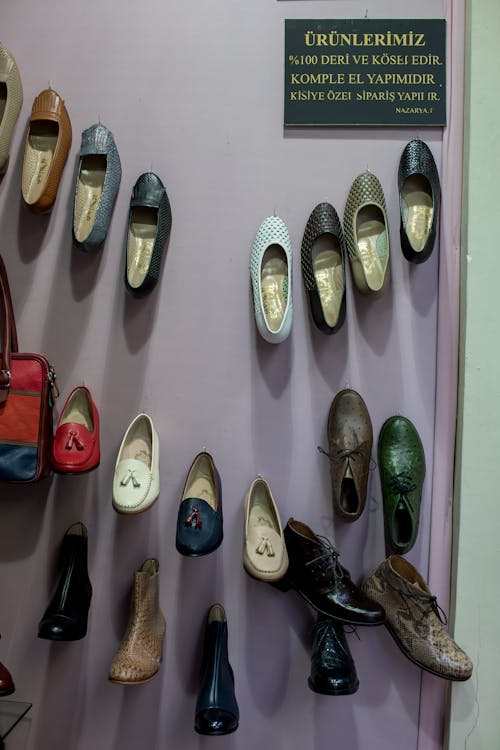 Collection of handmade leather shoes hanging on wall in manufacture
