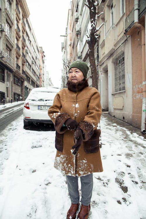 Calm Asian woman standing on snowy street in city