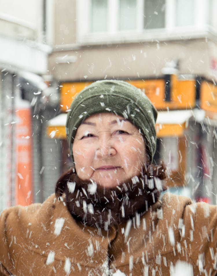 Senior Asian Woman Standing On Street In Snowy Day