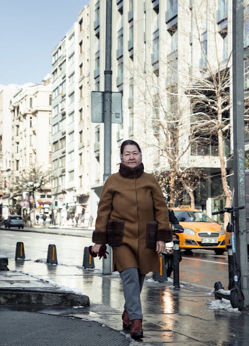 Asian woman walking on street in city in sunlight