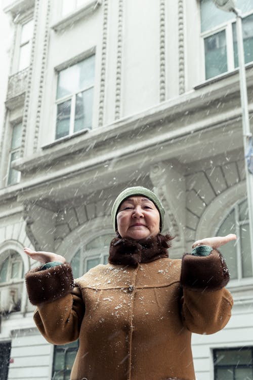 Elderly Asian woman in outerwear standing on city street in winter time