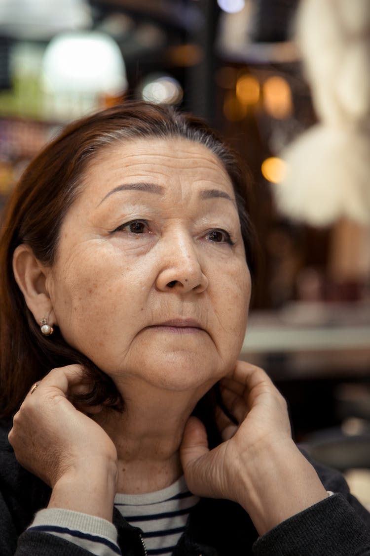 Pensive Elderly Woman Looking Away Against Blurred Background