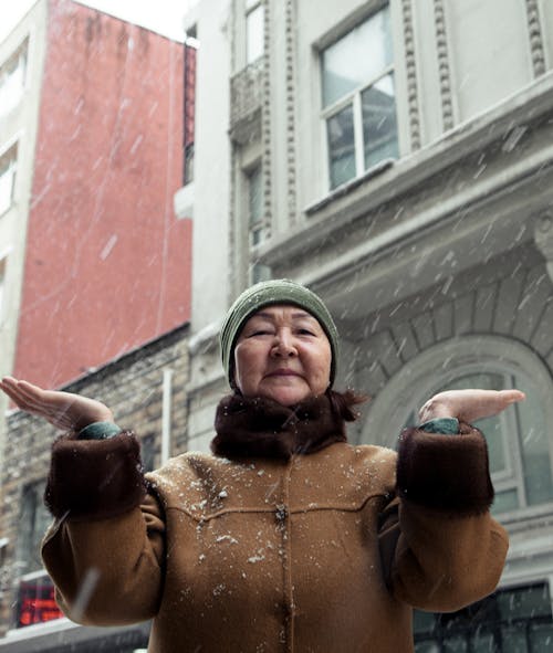 Senior Asian woman standing on street in snowy day