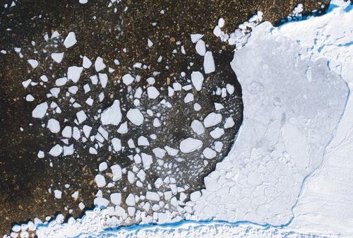 Free Aerial shot of ice pieces scattered across a dark lake, with snow and frozen water in winter. Stock Photo