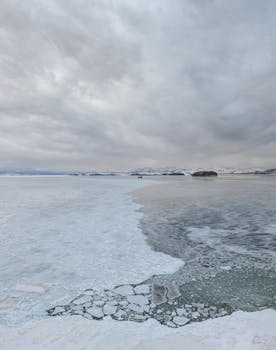 A breathtaking aerial view of a frozen seascape in Khasansky District, Russia, showcasing ice formations under a cloudy winter sky.