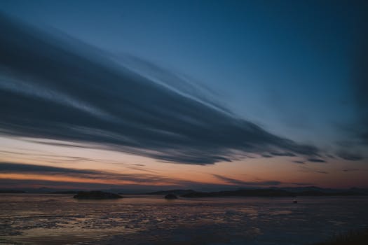 A breathtaking view of the Arctic sunset over calm ocean waters with distant islands.