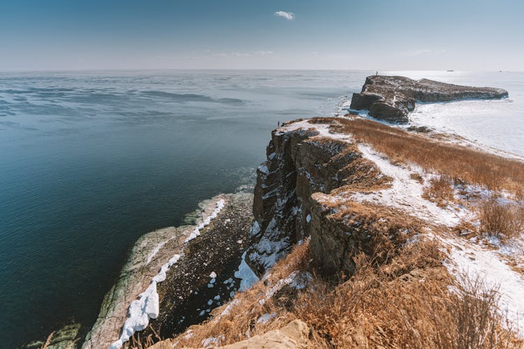 Brown Rocky Mountain Beside The Sea Under Blue Sky