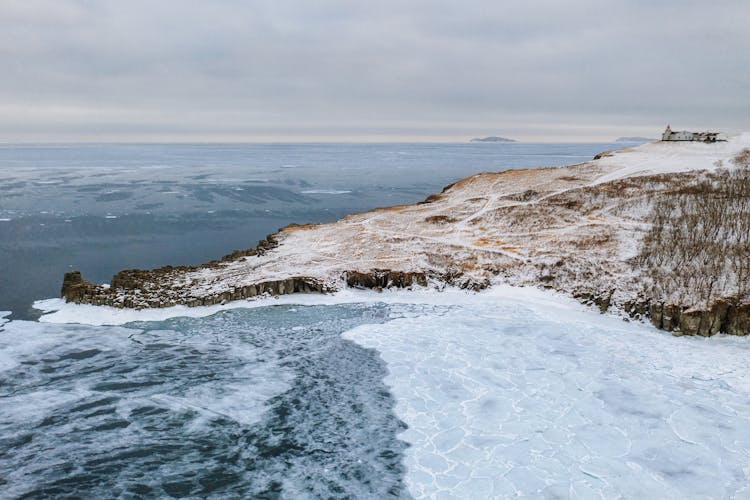 Snowy Brown Mountain Beside Body Of Water