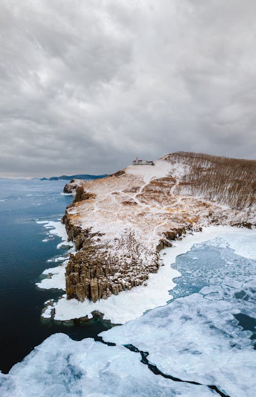 Brown Rocky Mountain Beside the Frozen Body of Water