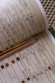 Vintage notebook with artistic swatches, showcasing historic color samples and a pen and pencil on the surface.