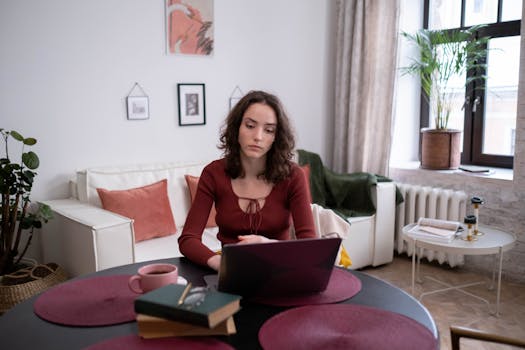 Woman working on a laptop in a cozy living room, illustrating remote work lifestyle.