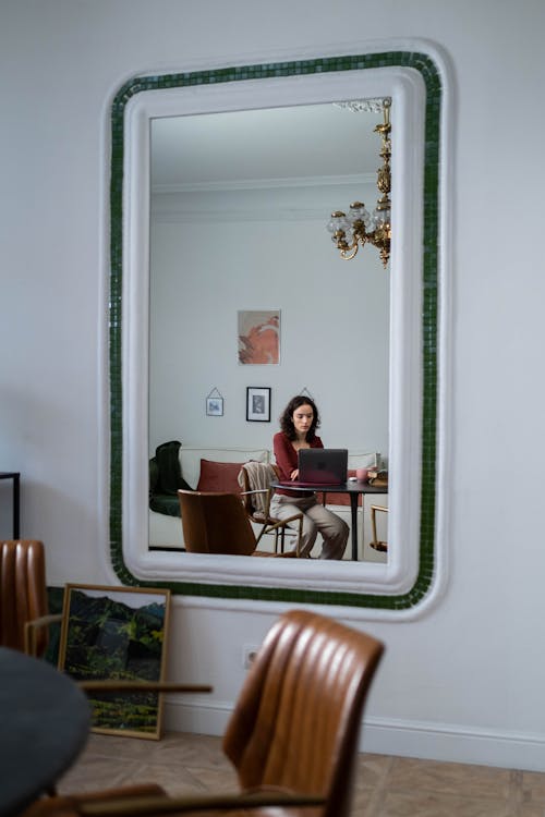 Mirror Reflection of a Woman Working on a Laptop
